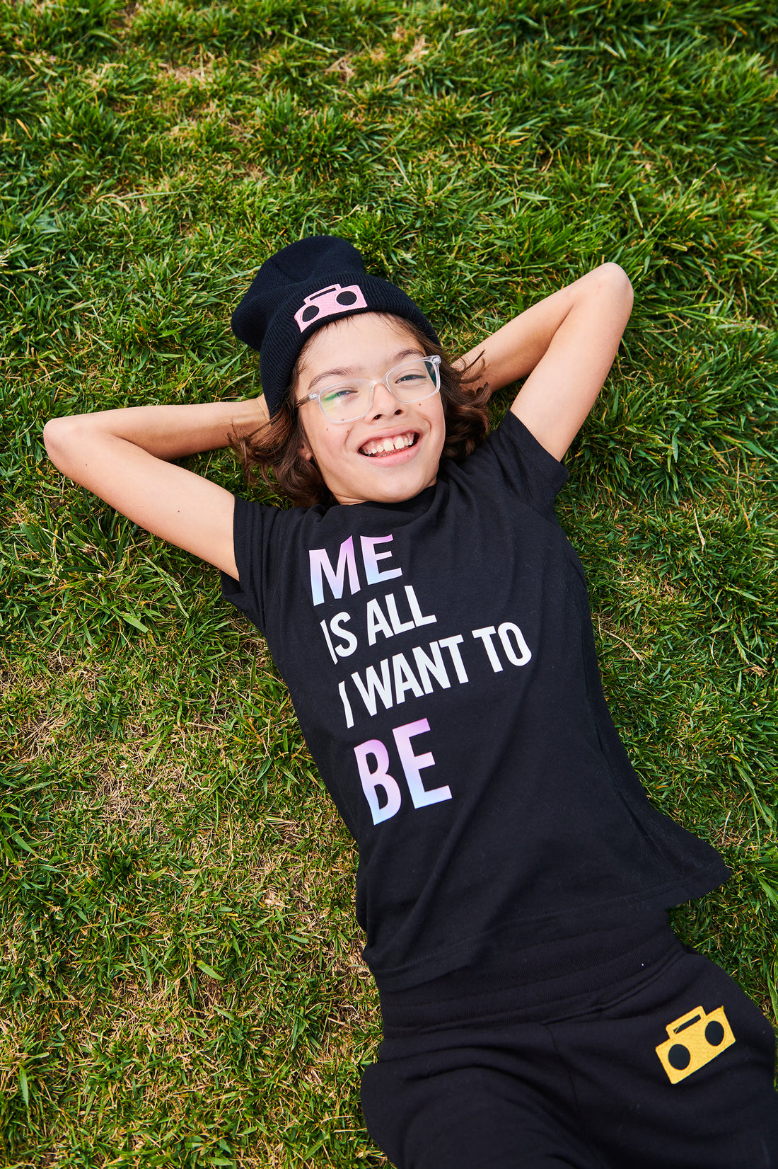 Cofounder of StereoType Kids, Jacob expresses himself freely lying on the grass, wearing brand tagline "Me Is All I Want To Be" T-Shirt 