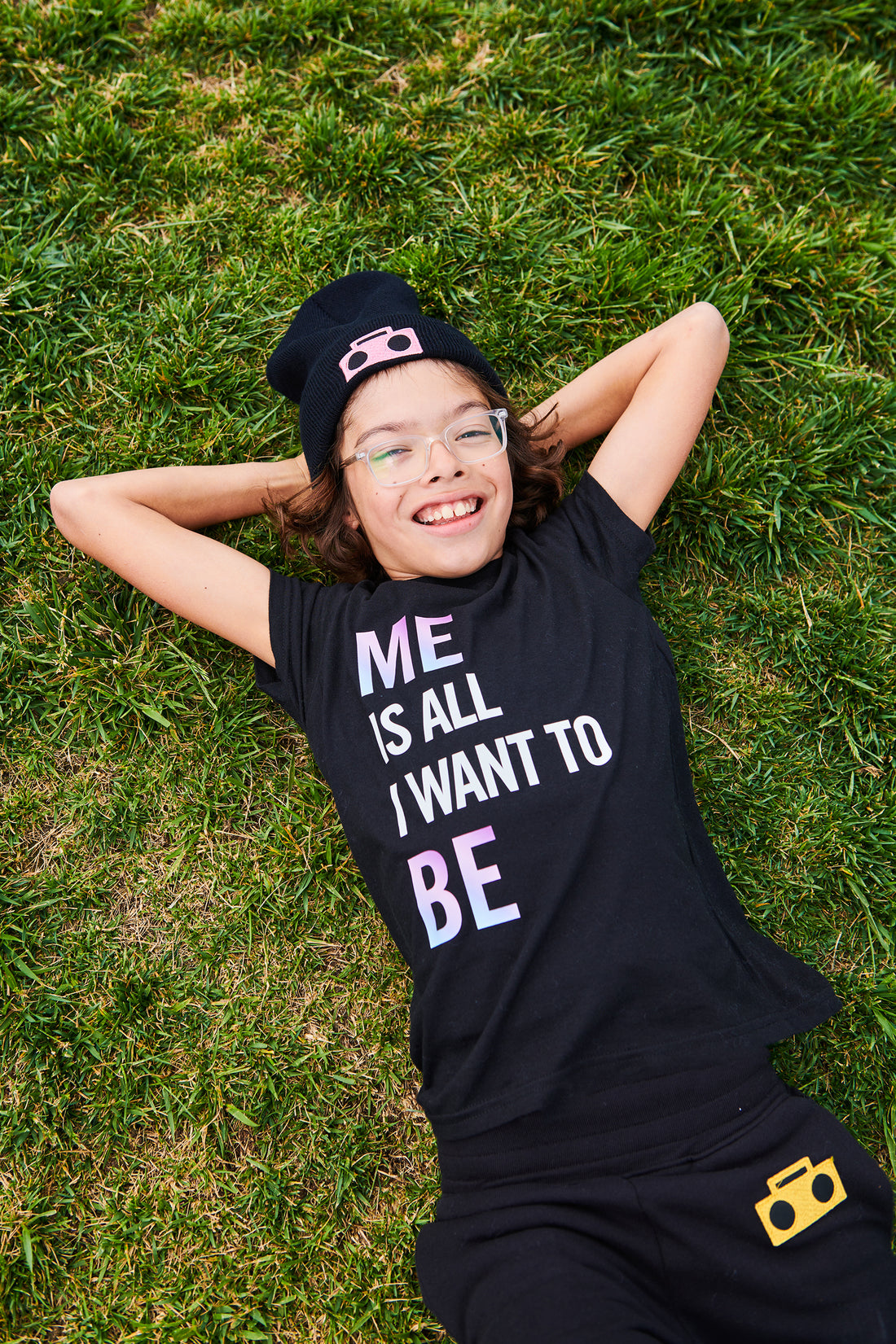 Cofounder of StereoType Kids, Jacob expresses himself freely lying on the grass, wearing brand tagline "Me Is All I Want To Be" T-Shirt