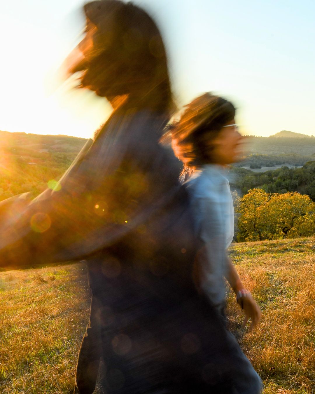 Chloe and Jacob running through a sunlit field at sunset, symbolizing childhood freedom, individuality, authenticity, and self-expression.