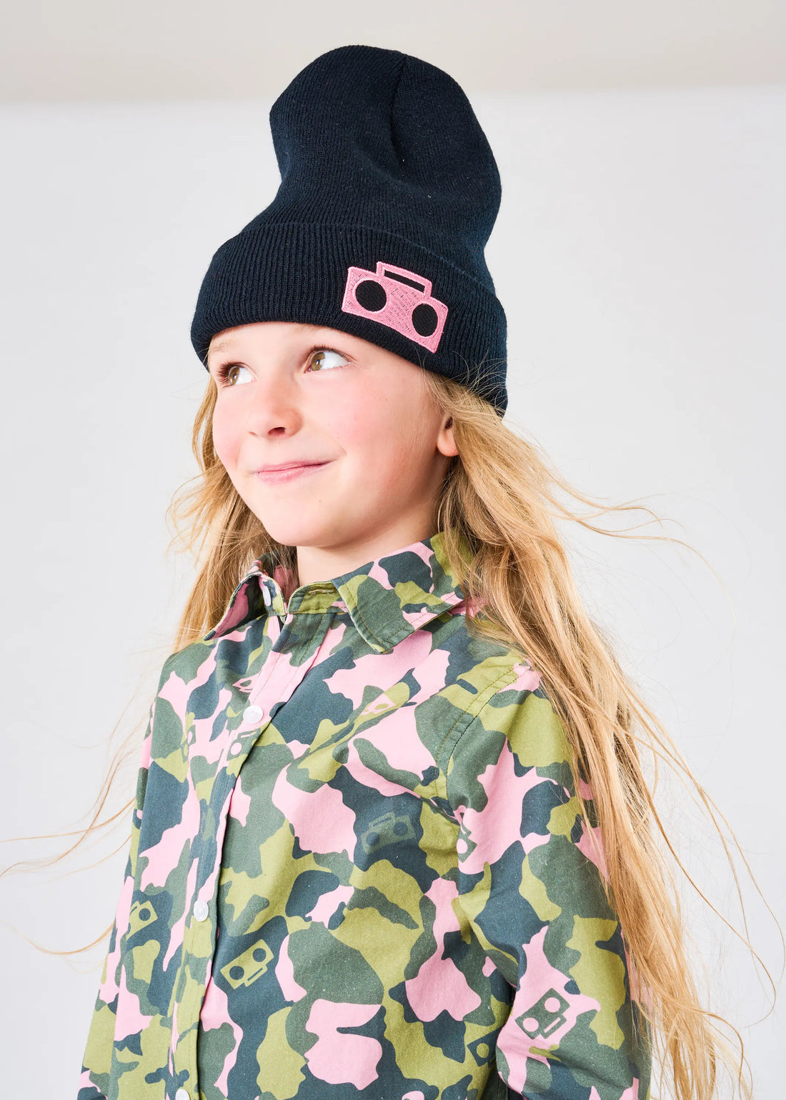 Child wearing StereoType Kids pink Boombox Knit Beanie and Camo Button-Down Zip Shirt