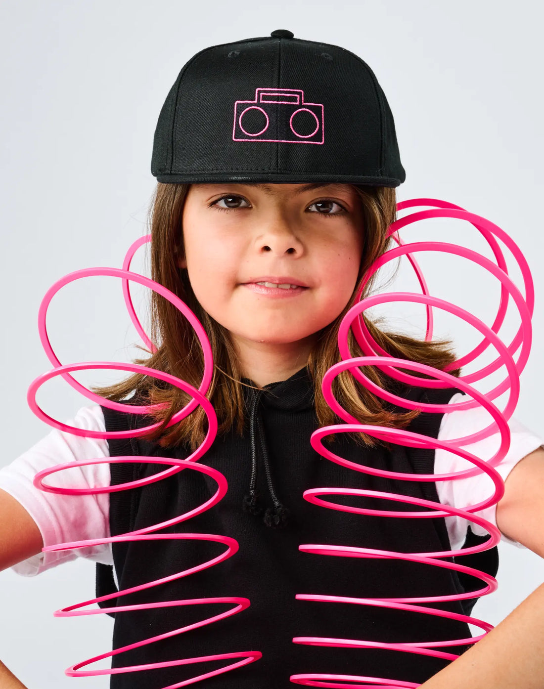 Co-founder Chloe Brunner wearing StereoType Kids black Boombox Baseball Cap with pink embroidered logo, holding pink slinky