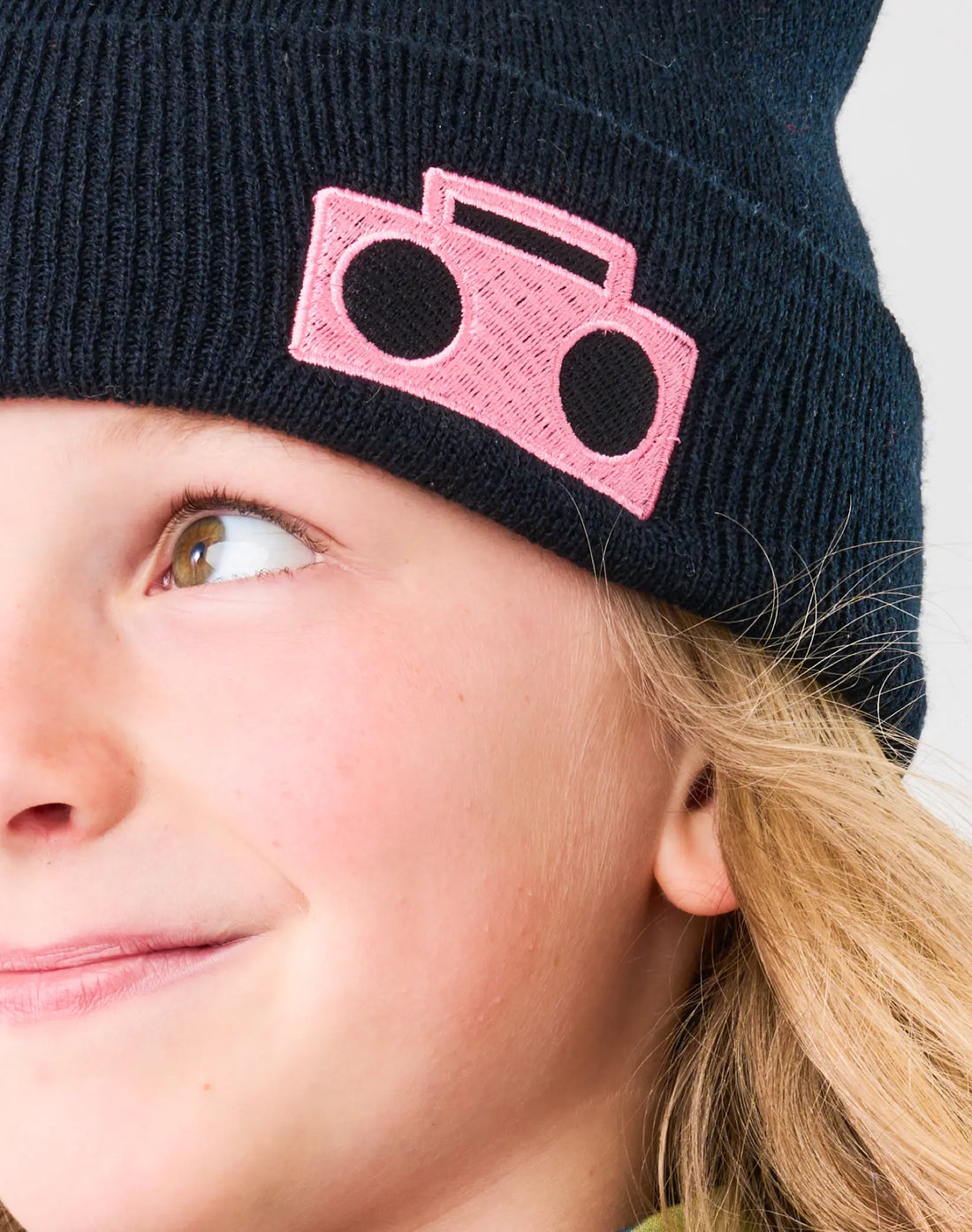 Close-up of StereoType Kids Boombox Beanie showing hot pink Boombox logo embroidered patch on black acrylic knit, embroidered in San Francisco