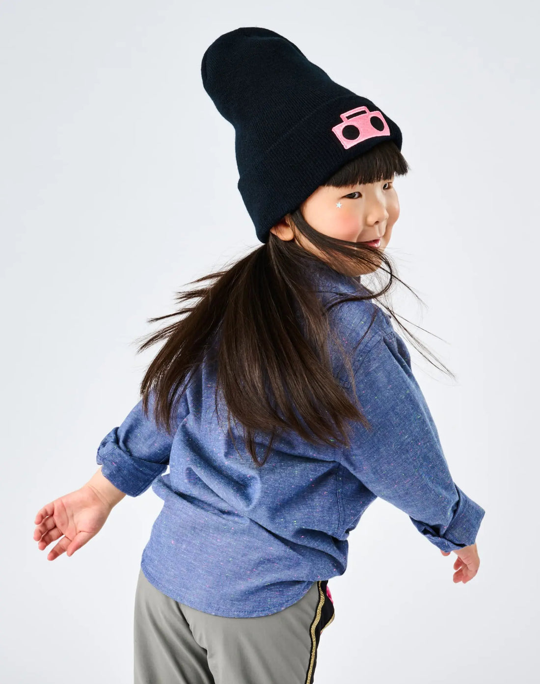 Child spinning wearing StereoType Kids Boombox Beanie in black with hot pink Boombox patch, Chambray Button-Down Zip Shirt and Active Pant, unisex kids gender-inclusive fashion