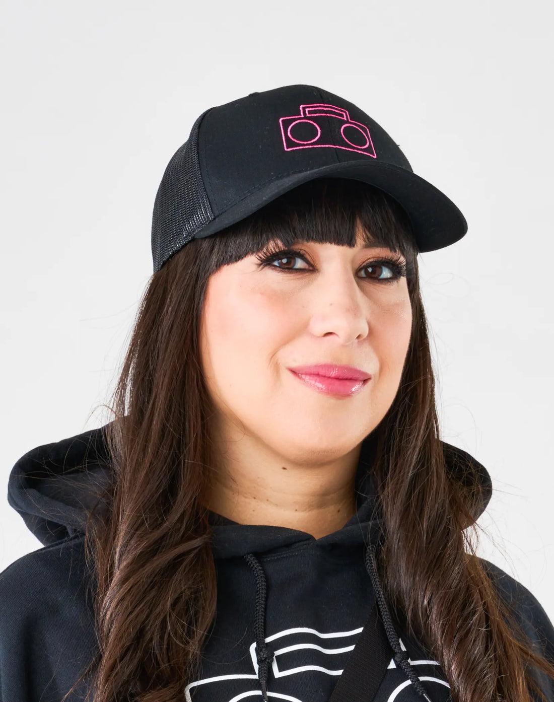 Adult wearing StereoType Kids black Boombox Trucker Cap with pink embroidered logo and black Boombox Logo Hoodie
