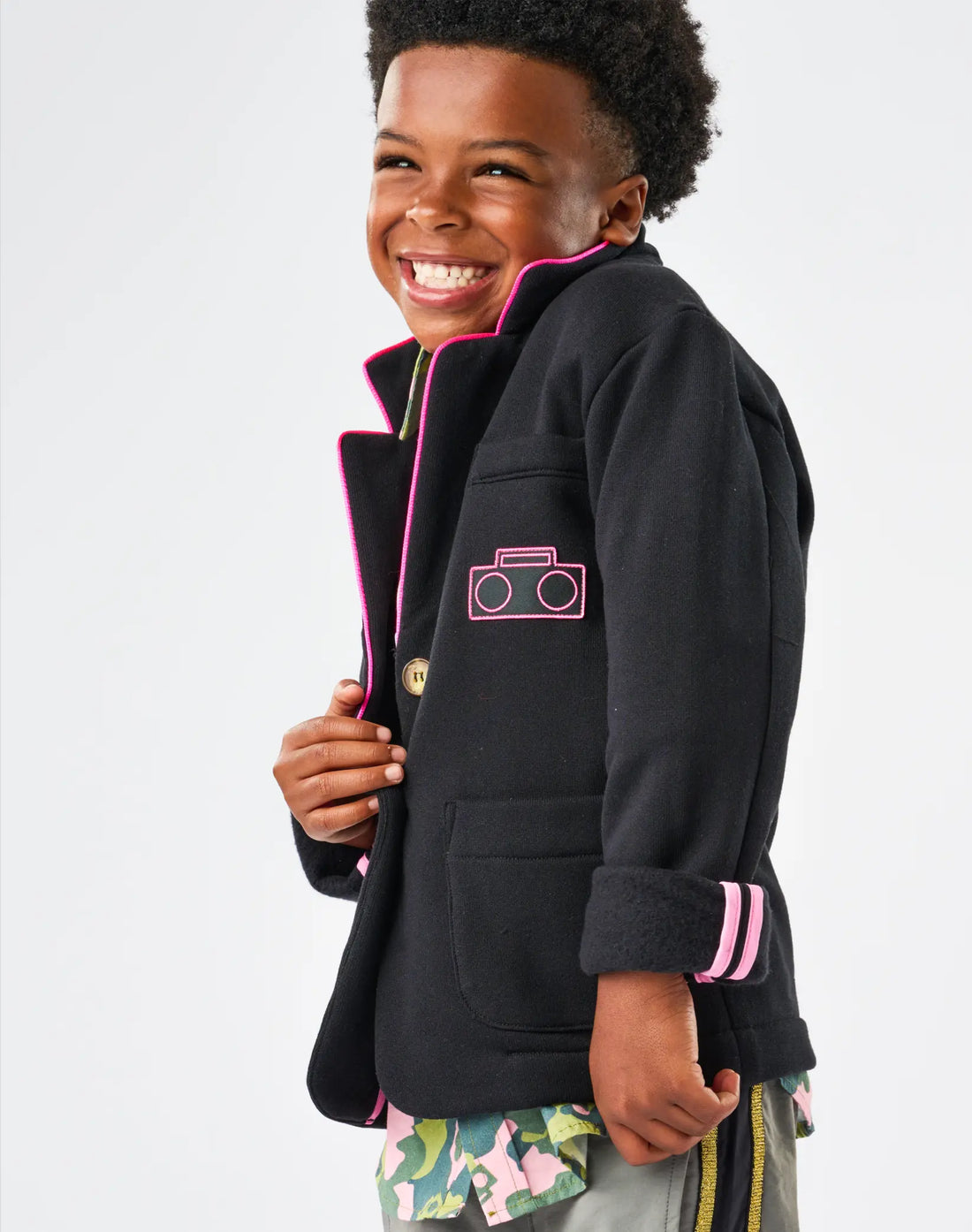 Child wearing StereoType Kids Hot Pink Boombox Blazer open to reveal pink ribbon interior seams, styled with Camo Button-Down Zip Shirt and Active Pant, unisex kids sustainable blazer
