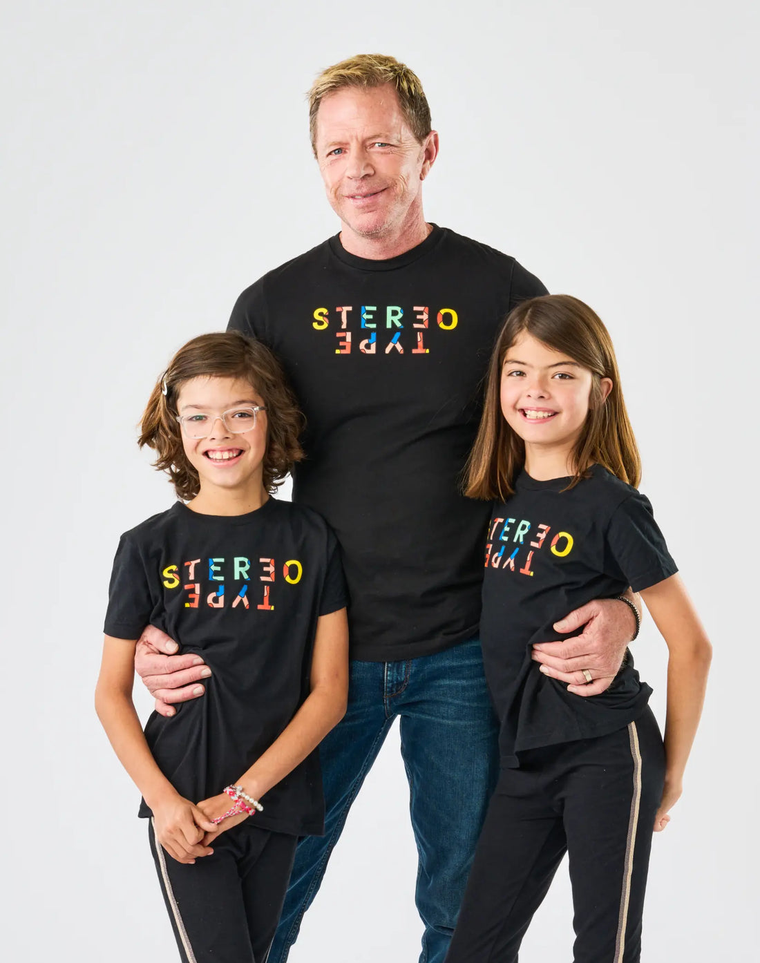 StereoType Kids co-founders Chloe and Jacob wearing youth Kaleidoscope Logo Tees with adult wearing matching unisex adult Kaleidoscope Logo Tee in black, gender-inclusive Mini-Me fashion