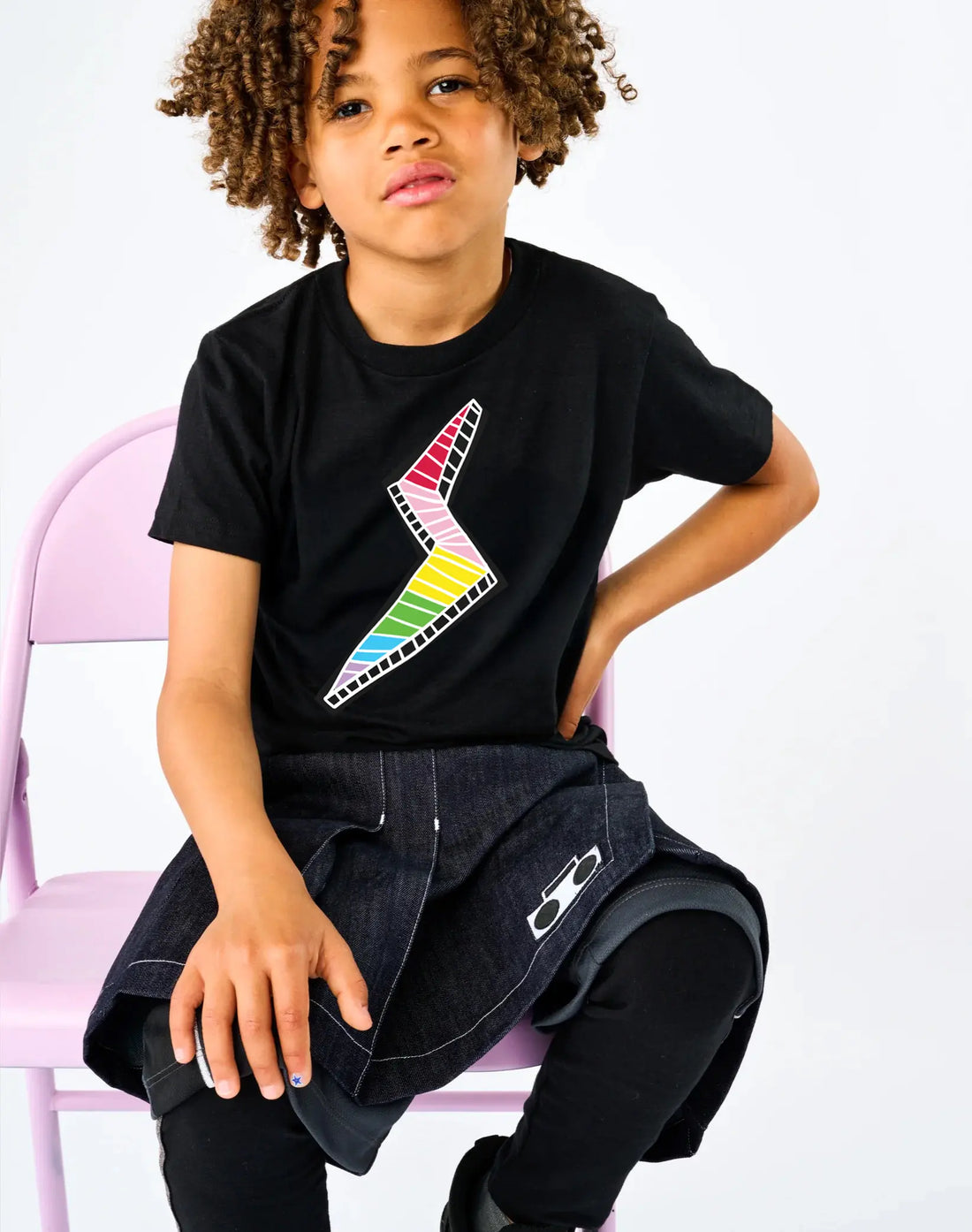 Child wearing StereoType Kids Lightning Bolt unisex kids black graphic tee with rainbow bolt designed by co-founder Chloe, styled with Athletic Skort and Sparkle Leggings
