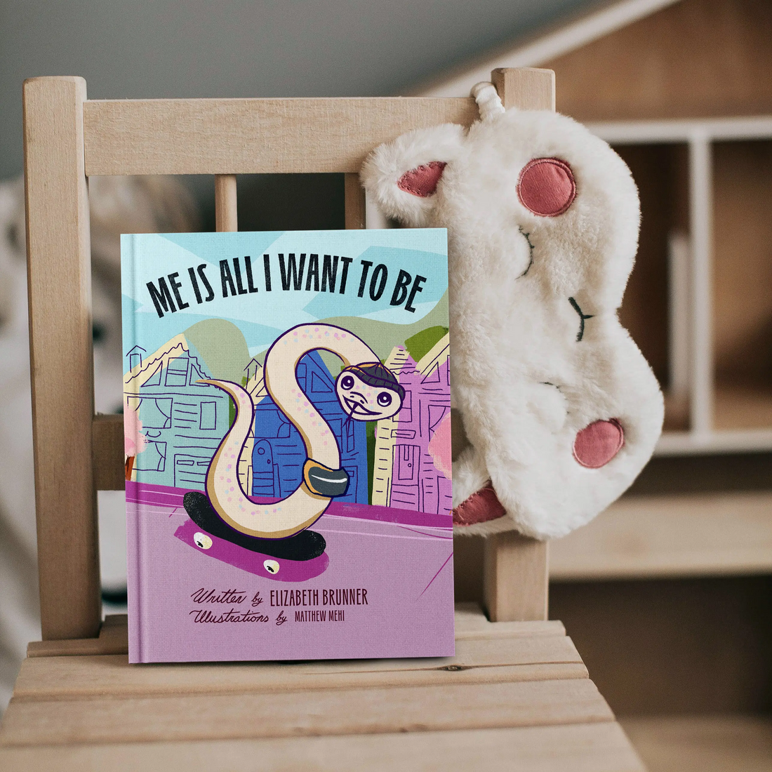 Me Is All I Want To Be hardcover children's book by Elizabeth Brunner displayed on a wooden chair with a stuffed animal