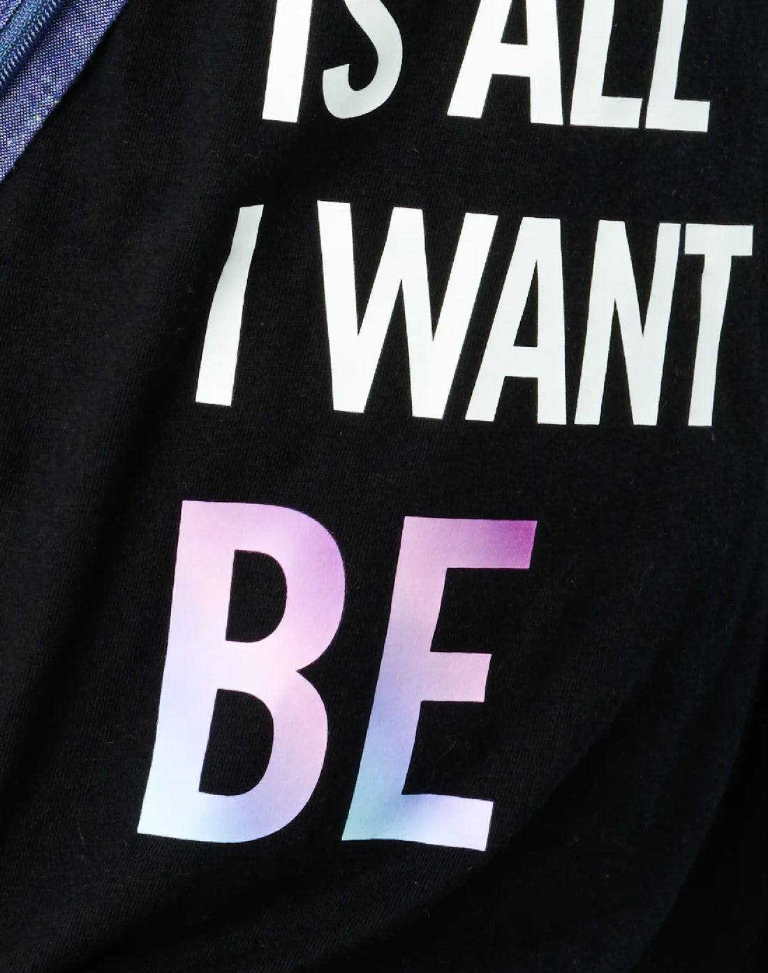 Close-up detail of StereoType Kids Me Is All I Want To Be tee showing holographic BE lettering and white IS ALL I WANT TO screen print on black cotton