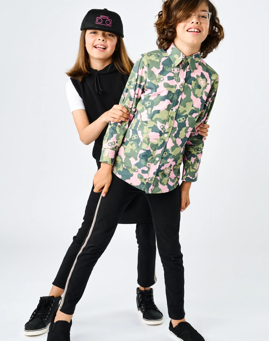 StereoType Kids co-founders Chloe and Jacob wearing Sparkle Leggings in black with gold sparkle stripe, Boombox Baseball Cap and Camo Button-Down Zip Shirt, gender-inclusive unisex kids fashion