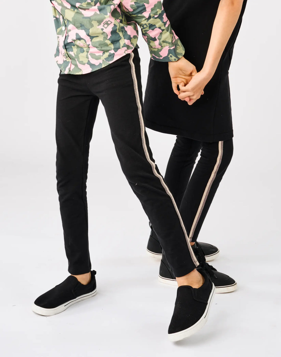 StereoType Kids co-founders Chloe and Jacob wearing Sparkle Leggings in black with gold sparkle stripe, holding hands, unisex kids gender-inclusive leggings designed in San Francisco