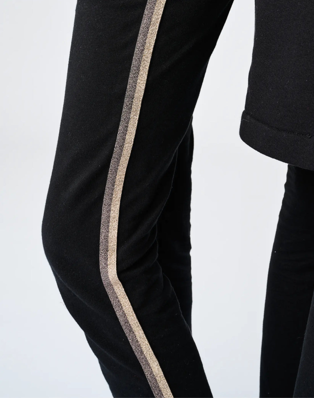 Close-up detail of StereoType Kids Sparkle Leggings showing signature gold sparkle stripe down the leg on black knit cotton spandex