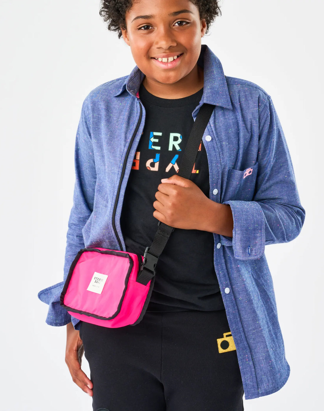 Stereotype Kids Boombox Treasure Bag worn crossbody in hot pink reversible side by child in chambray shirt