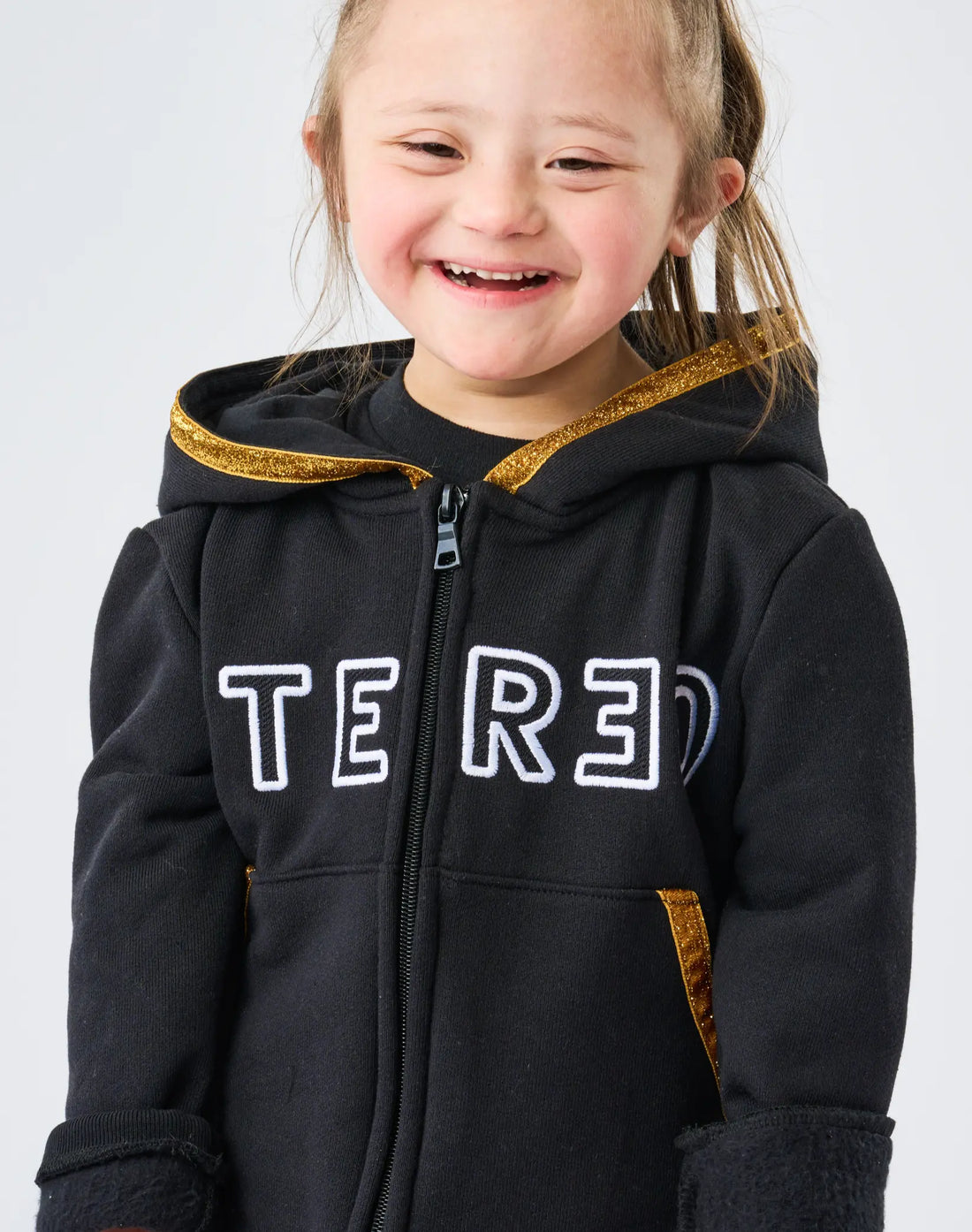 Child wearing a black hoodie with 'TRED' branding on a white background